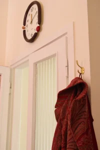 Particolare della porta d&rsquo;ingresso dello studio di psicologia Cinque Vie con appendiabiti dorato e orologio da parete