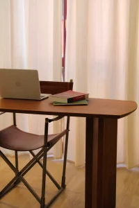 Scrivania in legno con laptop e libri di psicologia nello studio Cinque Vie, sedia in pelle e luce naturale morbida